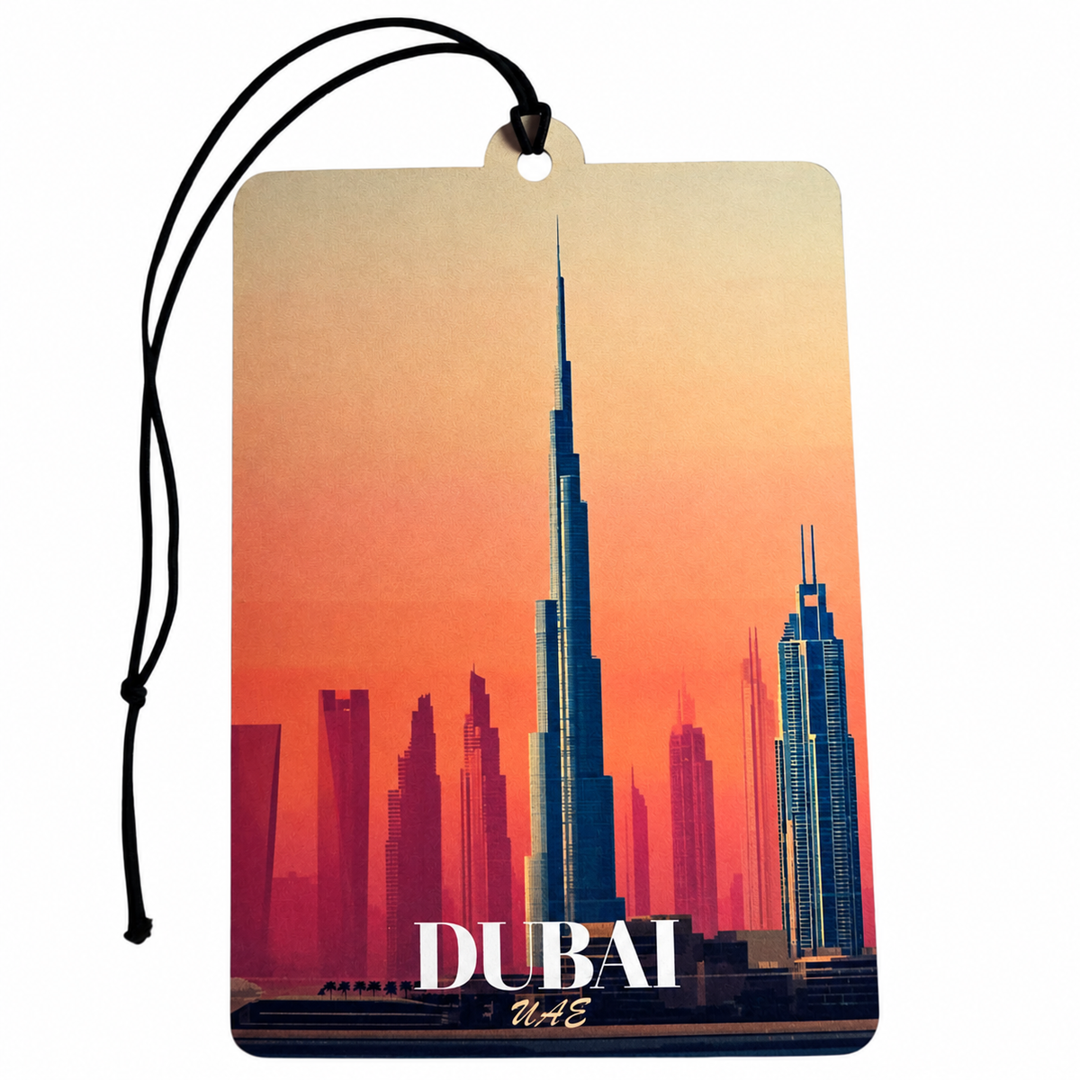 A rectangular Dubai car air freshener tag featuring a sunset skyline of Burj Khalifa and other skyscrapers, with 'DUBAI' and 'UAE' printed at the bottom, suspended by a black cord on a white background.