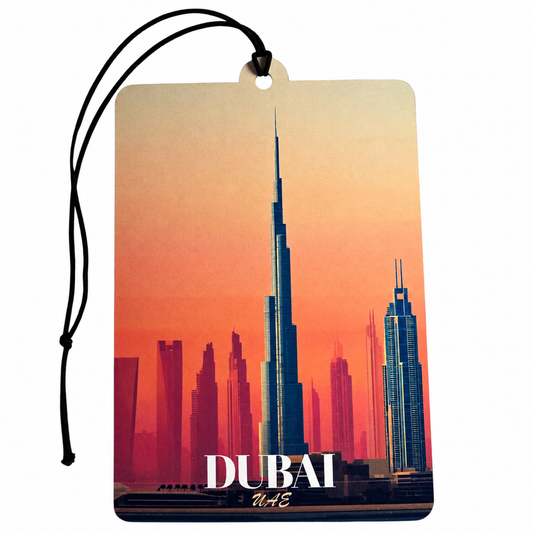 A rectangular Dubai car air freshener tag featuring a sunset skyline of Burj Khalifa and other skyscrapers, with 'DUBAI' and 'UAE' printed at the bottom, suspended by a black cord on a white background.