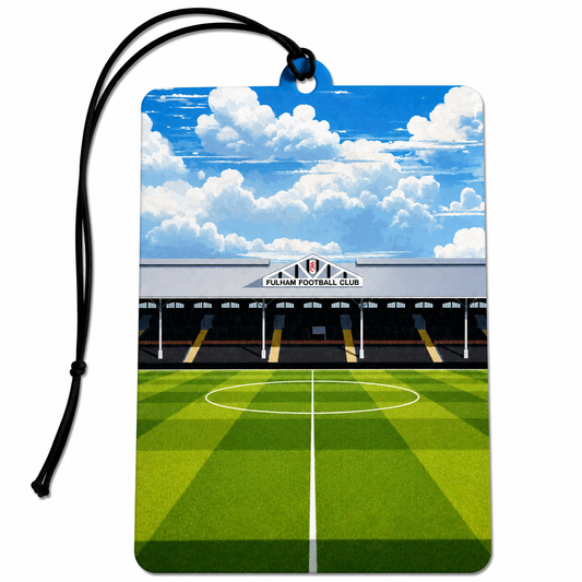 Fulham FC inspired car air freshener featuring a Craven Cottage-style football stadium stand, black and white details and a green football pitch beneath a cloudy blue sky.