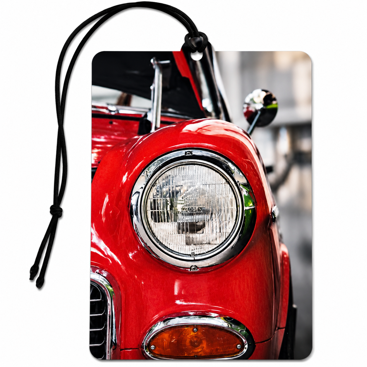 A rectangular luggage tag or car air freshener featuring a close-up photographic print of a classic red car, complete with a black hanging strap and a small metal ring at the top.