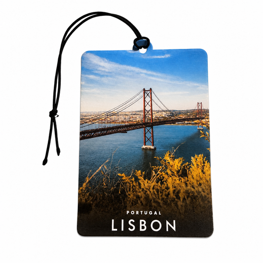 A rectangular car air freshener with a black hanging cord, printed with a scenic photograph of the Lisbon 25 de Abril Bridge over water, with 'PORTUGAL LISBON' text at the bottom, on a plain white background.