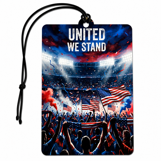A rectangular car air freshener tag with a black hanging cord, featuring a patriotic sports stadium graphic with the text 'UNITED WE STAND' in white at the top. The illustration shows a crowd cheering with American flags, smoke, and bright stadium lights in red, white, and blue.