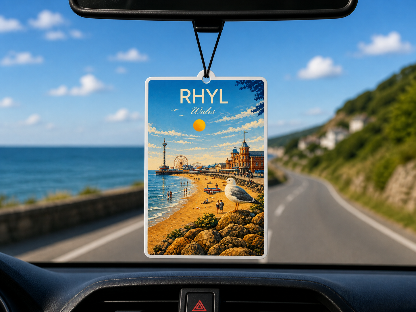 Car air freshener with a scenic view of Rhyl, Wales hanging from a car's rearview mirror.