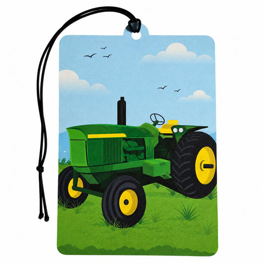 A rectangular hanging tag or car air freshener with a black cord loop at the top, printed with an illustration of a green tractor on grass under a blue sky with clouds and birds.