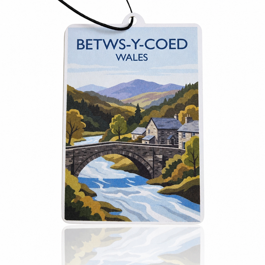 Car air freshener with a scenic illustration of Betws-y-Coed, Wales, featuring a bridge over a river and mountains.