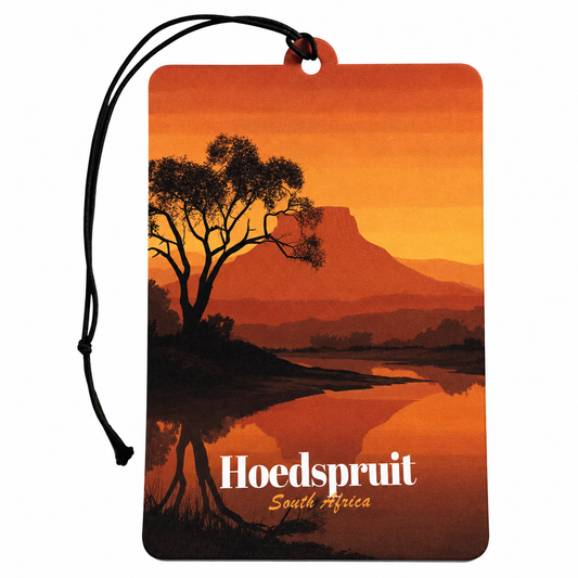 A rectangular car air freshener tag with a black hanging cord, featuring a scenic orange sunset landscape of Hoedspruit, South Africa, with a tree silhouette and the text 'Hoedspruit South Africa' printed on it.