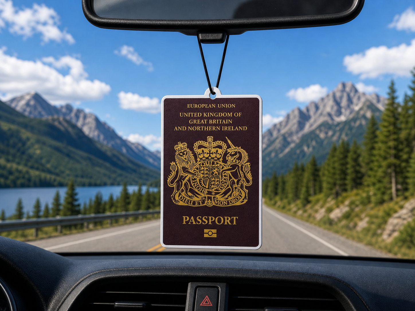 Passport-shaped air freshener on a car dashboard with a scenic road and mountains in the background