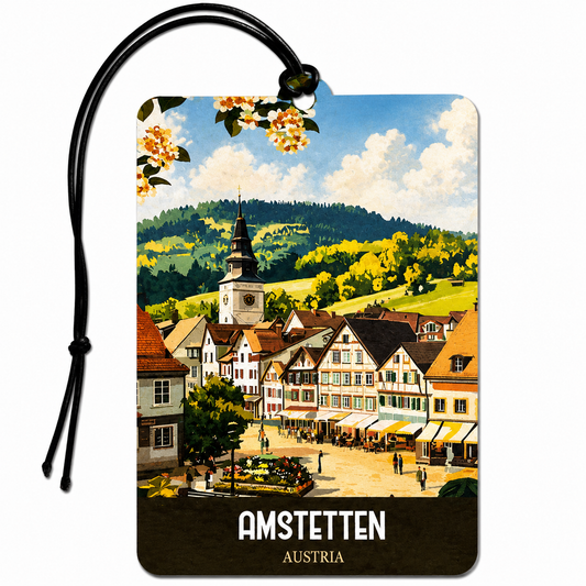 A rectangular luggage tag or travel tag with rounded corners, printed with a colorful scenic illustration of Amstetten, Austria. The tag has a black hanging loop and cord, and the text 'AMSTETTEN' and 'AUSTRIA' at the bottom.